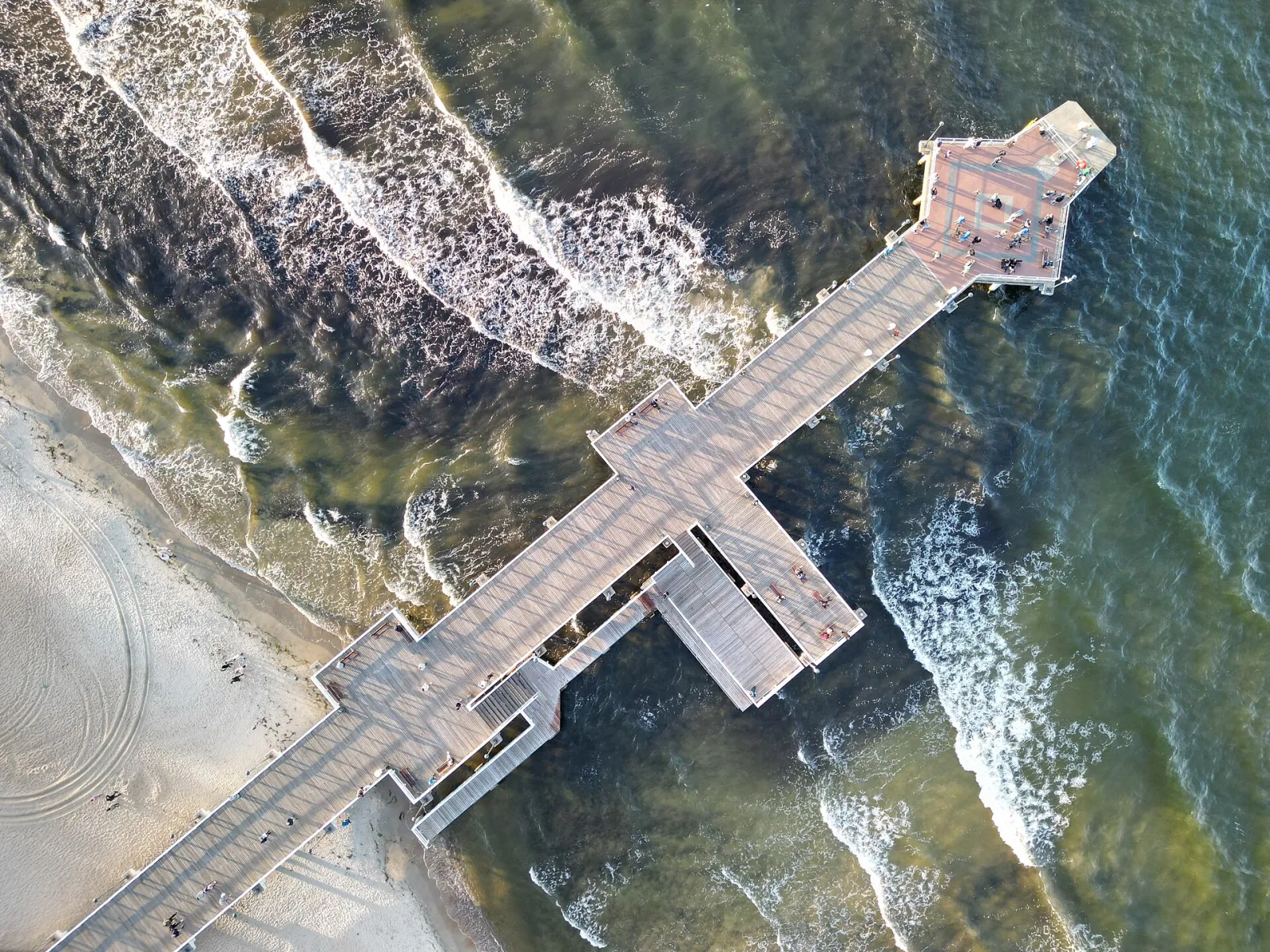 Molo w Brzeźnie widziane z góry, z plażą i falami Zatoki Gdańskiej