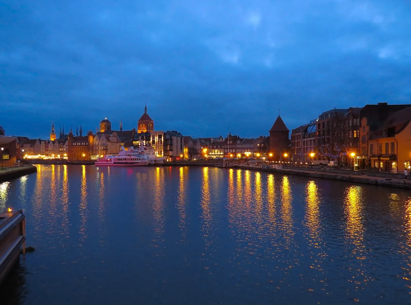 Wieczorna panorama Gdańska nad Motławą z odbiciami świateł w wodzie