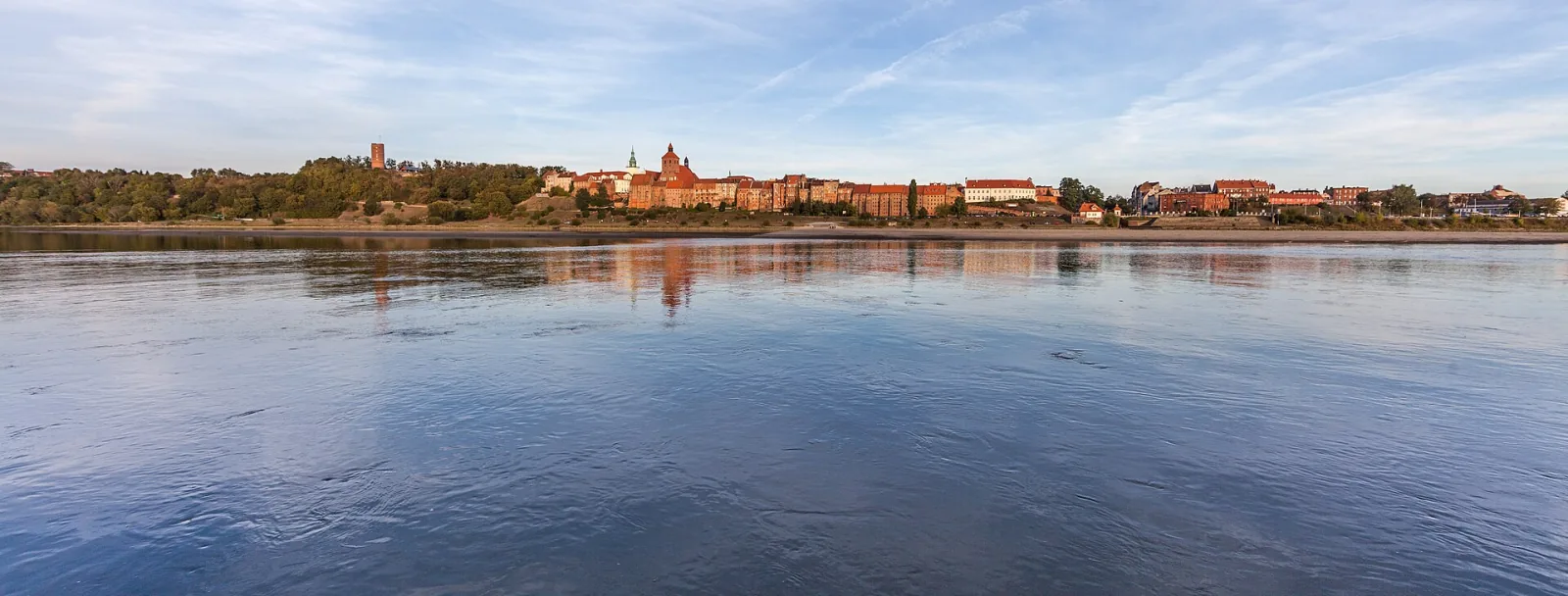 Rozległa panorama Grudziądza z kościołami i spichlerzami odbijająca się w Wiśle