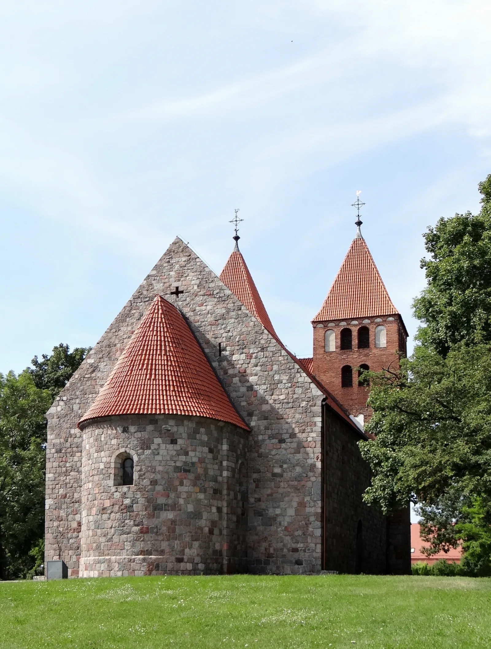 Kamienny kościół Imienia Najświętszej Maryi Panny w Inowrocławiu, ceglane wieże i zielony trawnik