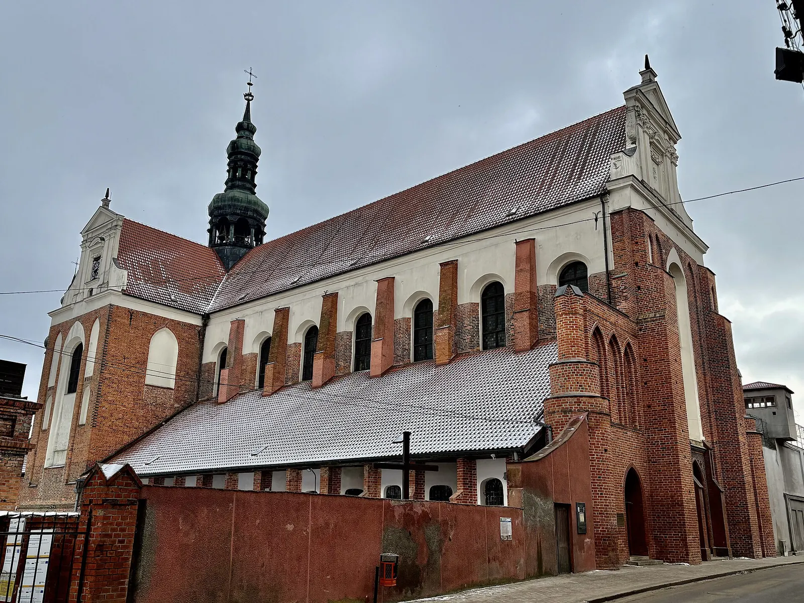 Boczna elewacja pocysterskiej bazyliki w Koronowie z ceglanymi przyporami i wysokim dachem