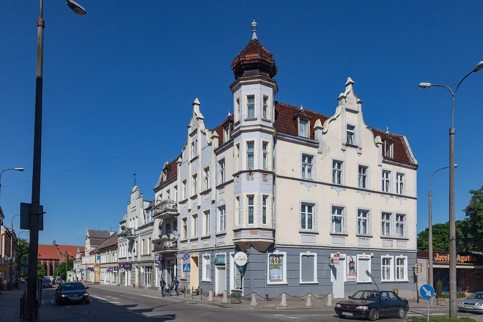Jasna kamienica z narożną wieżyczką przy ulicy Braterstwa Narodów w Kwidzynie na tle błękitnego nieba