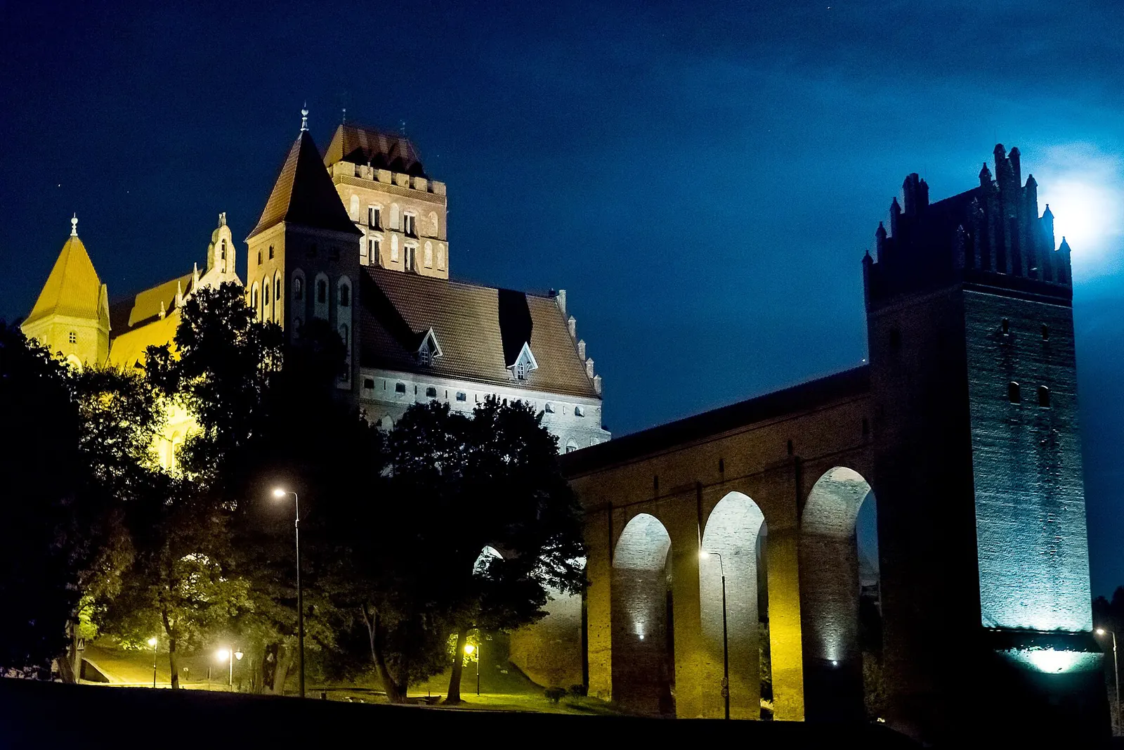 Nocny widok podświetlonego zamku w Kwidzynie i arkadowego ganku prowadzącego do gdaniska