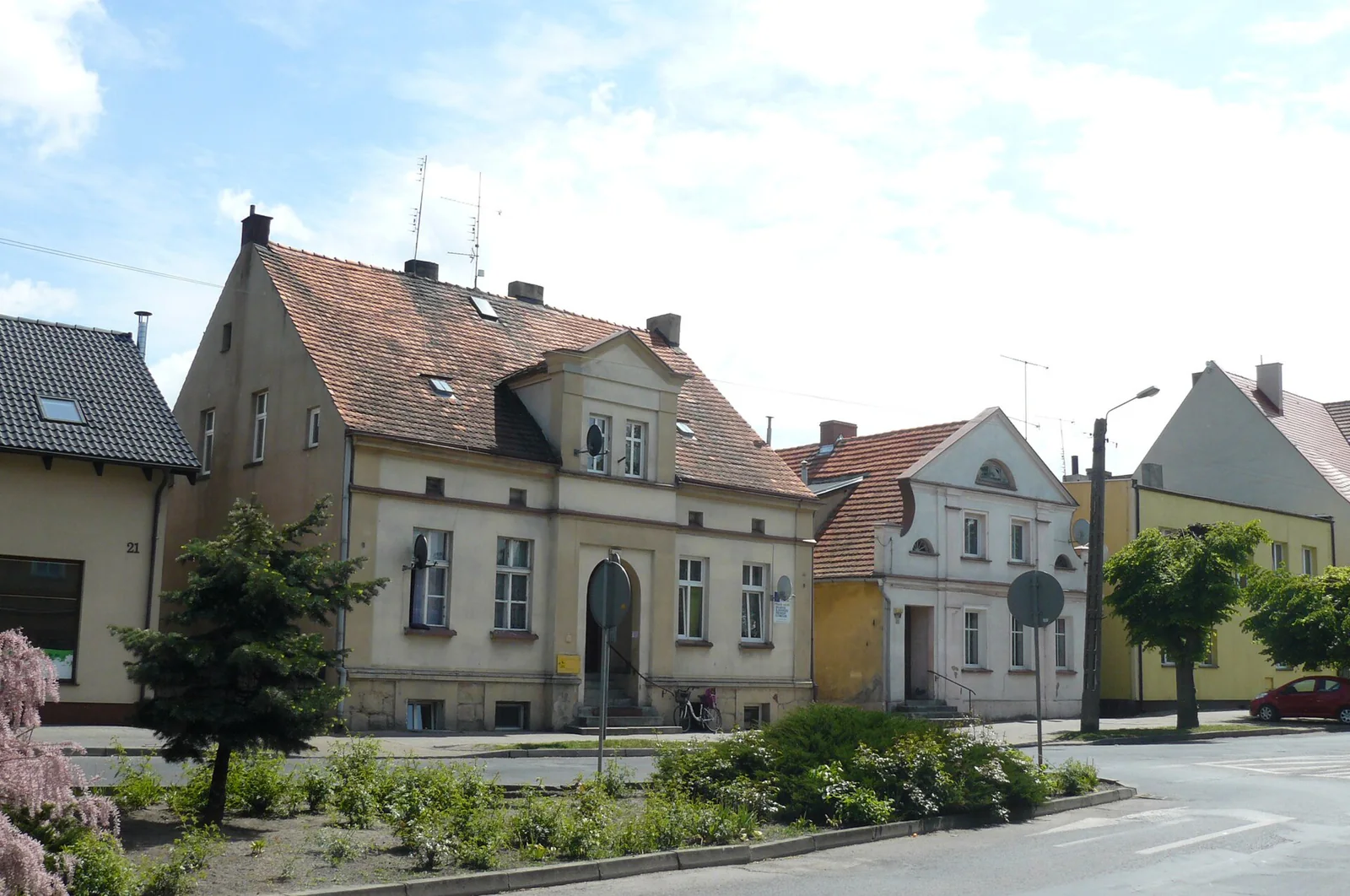 Jasne kamienice przy Rynku w Mogilnie, zielony skwer i zakręt ulicy w słoneczny dzień