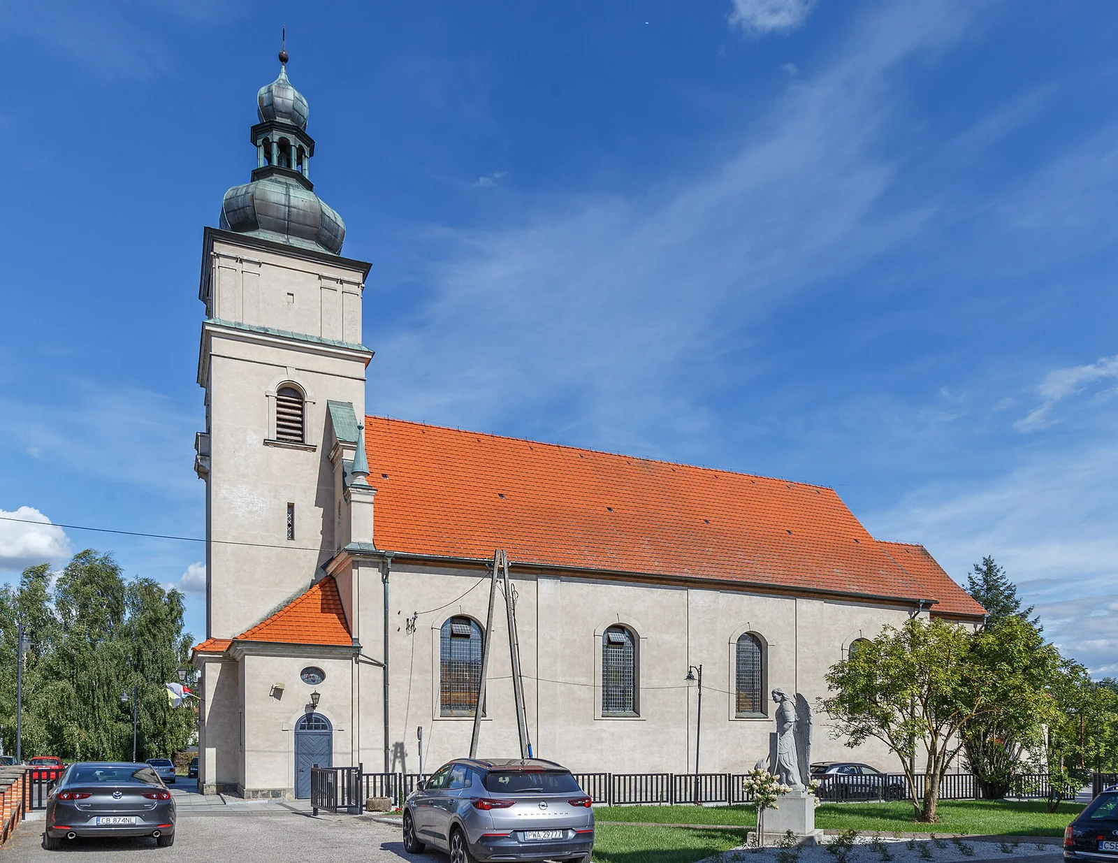 Kościół świętego Bartłomieja w Sępólnie Krajeńskim z jasną wieżą i czerwonym dachem pod błękitnym niebem