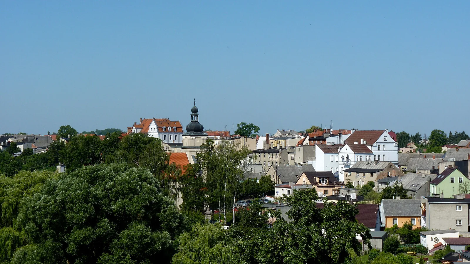 Panorama dachów Sępólna Krajeńskiego z wieżą kościoła i zielenią widziana ze skarpy przy ulicy Niechorskiej