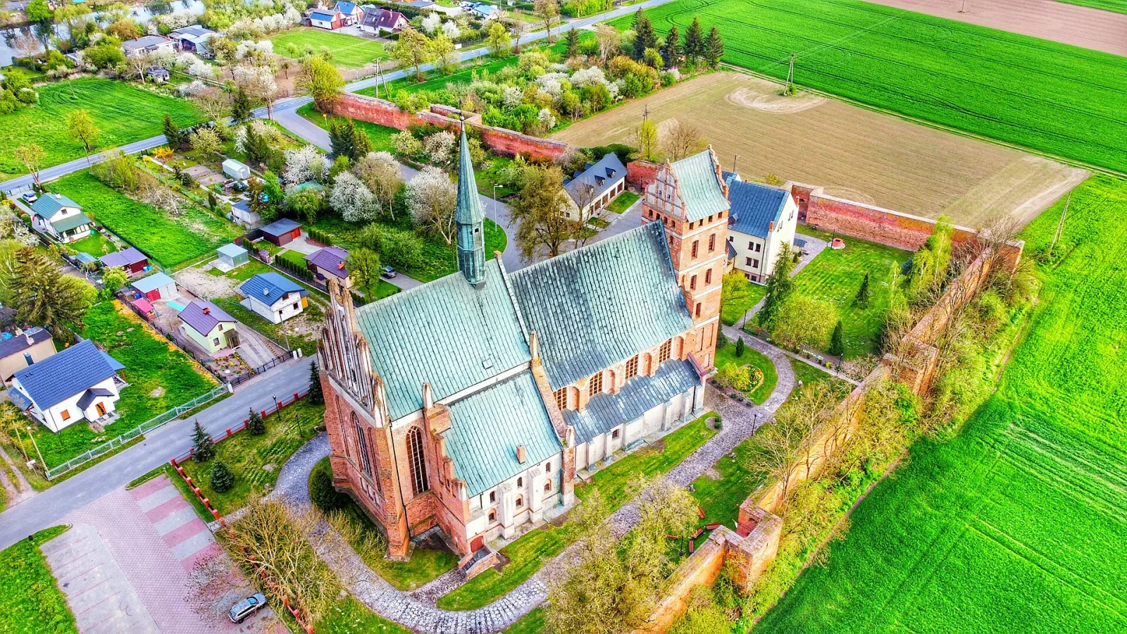 Gotycka fara w Świeciu widziana z góry, otoczona murami, zielenią i zabudowaniami