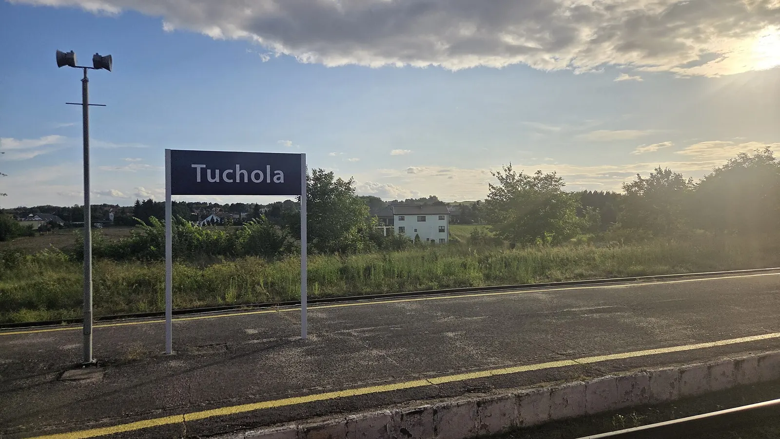 Peron stacji Tuchola z tablicą nazwy miejscowości w ciepłym świetle niskiego słońca